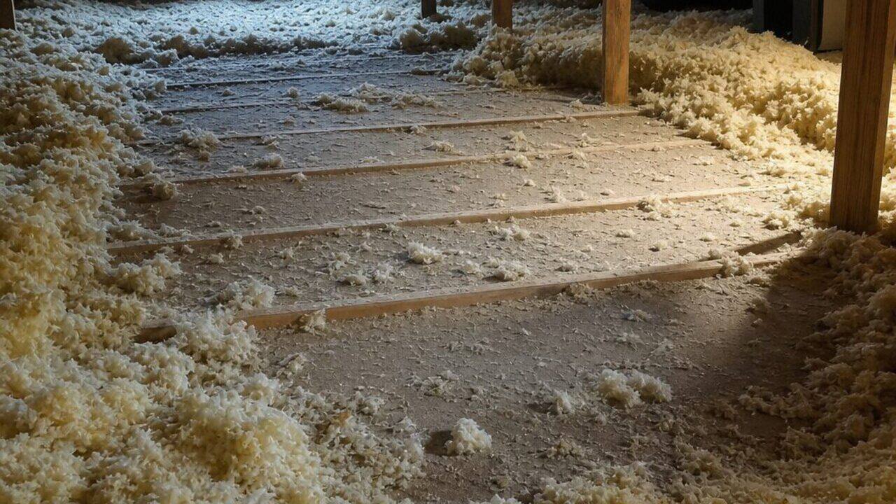 Attic floor where blown-in insulation has been flattened and pushed aside down to the bare ceiling deck and joists, leaving large uninsulated gaps, in a Newport News home
